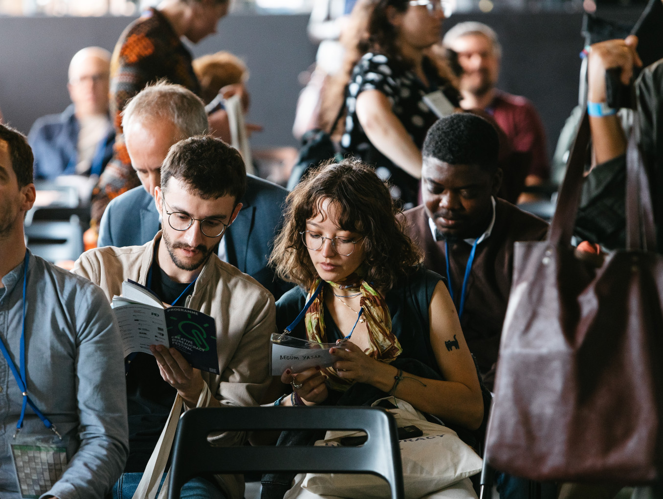 Das Publikum sitzt und schaut sich das Programm des Festivals an