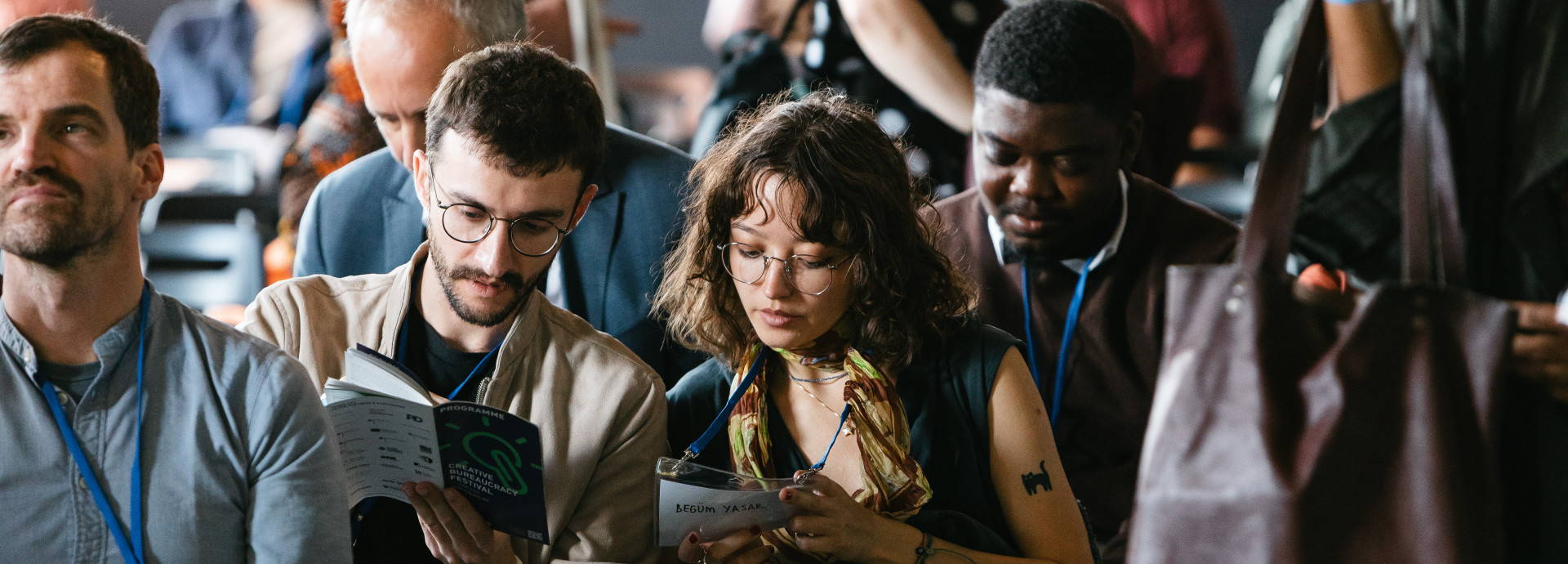 Das Publikum sitzt und schaut sich das Programm des Festivals an
