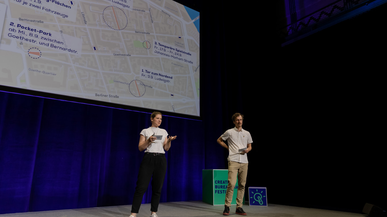 woman and man on stage holding a presentation 