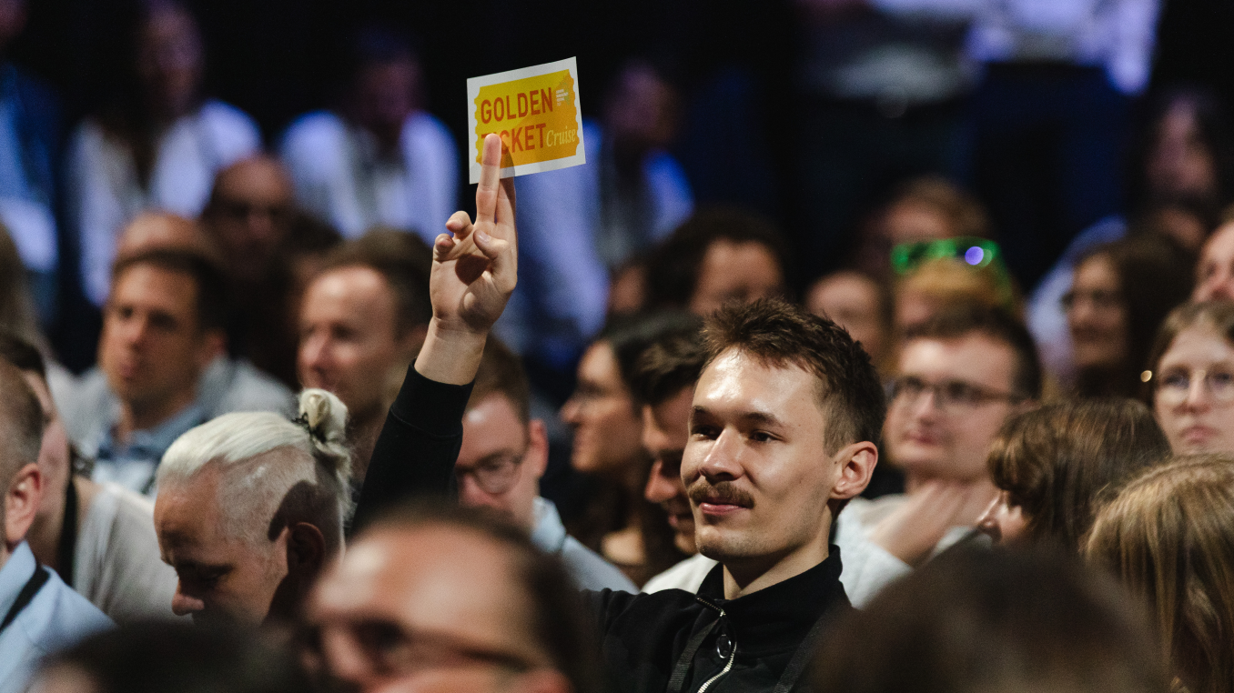 man won the golden ticket at the opening and is showing it by holding it in the air in the audience